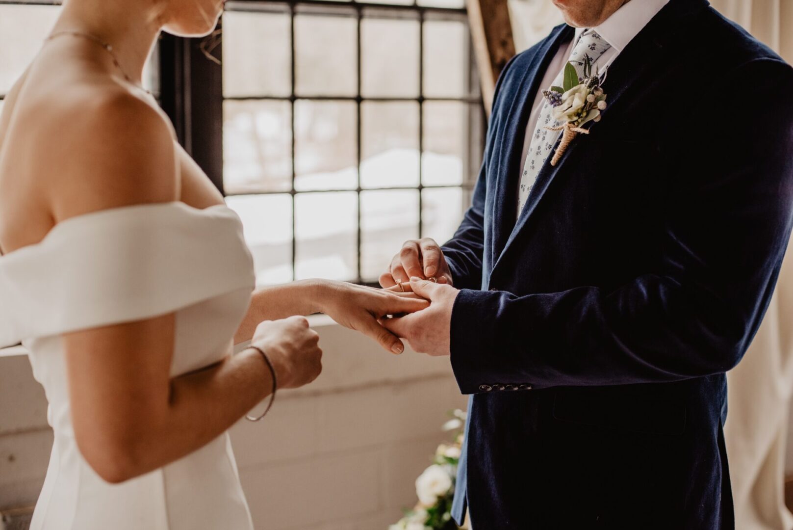 Close-up of a groom putting the ring on his bride’s finger